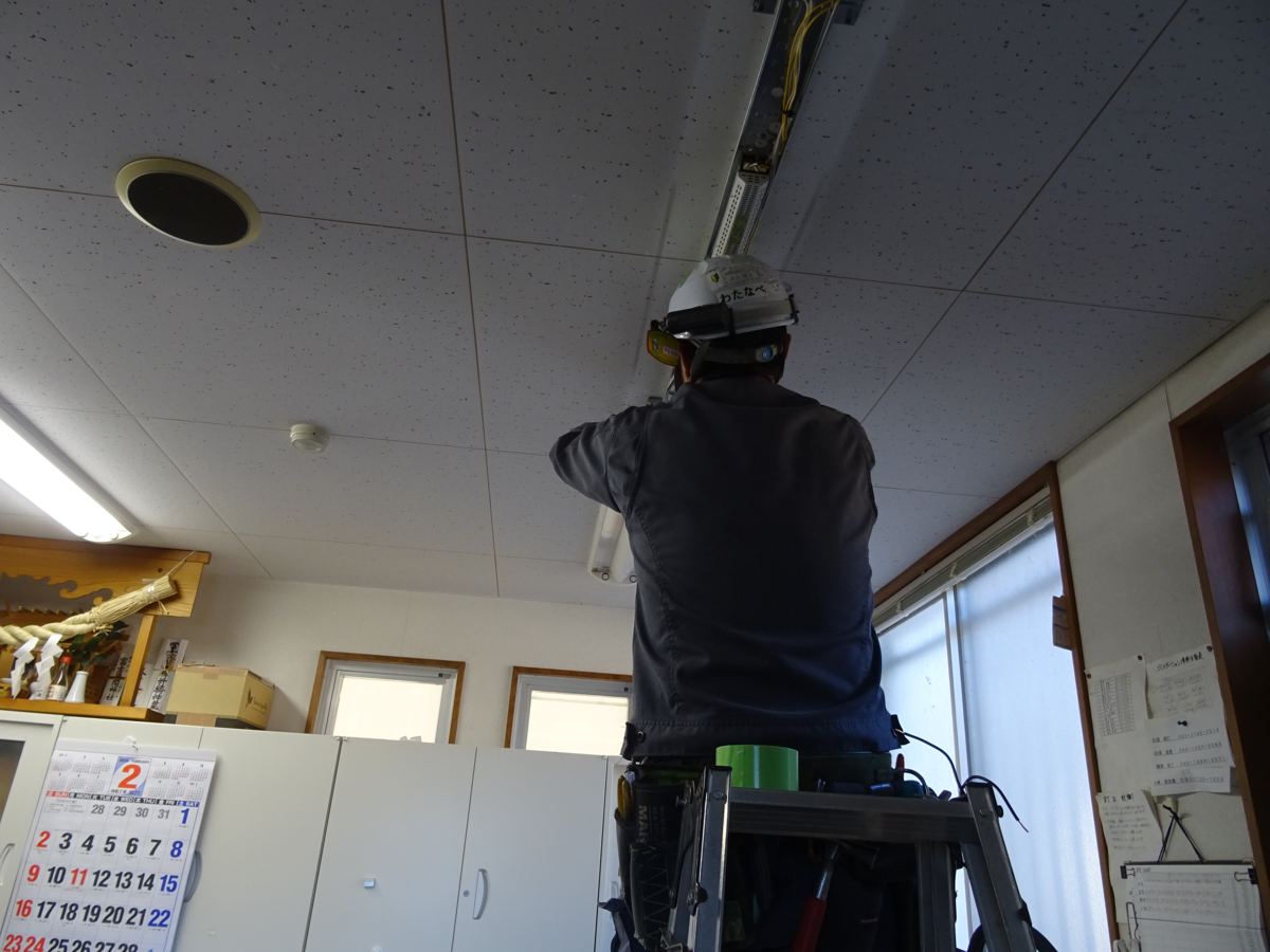天井の照明器具に配線を行うスタッフ