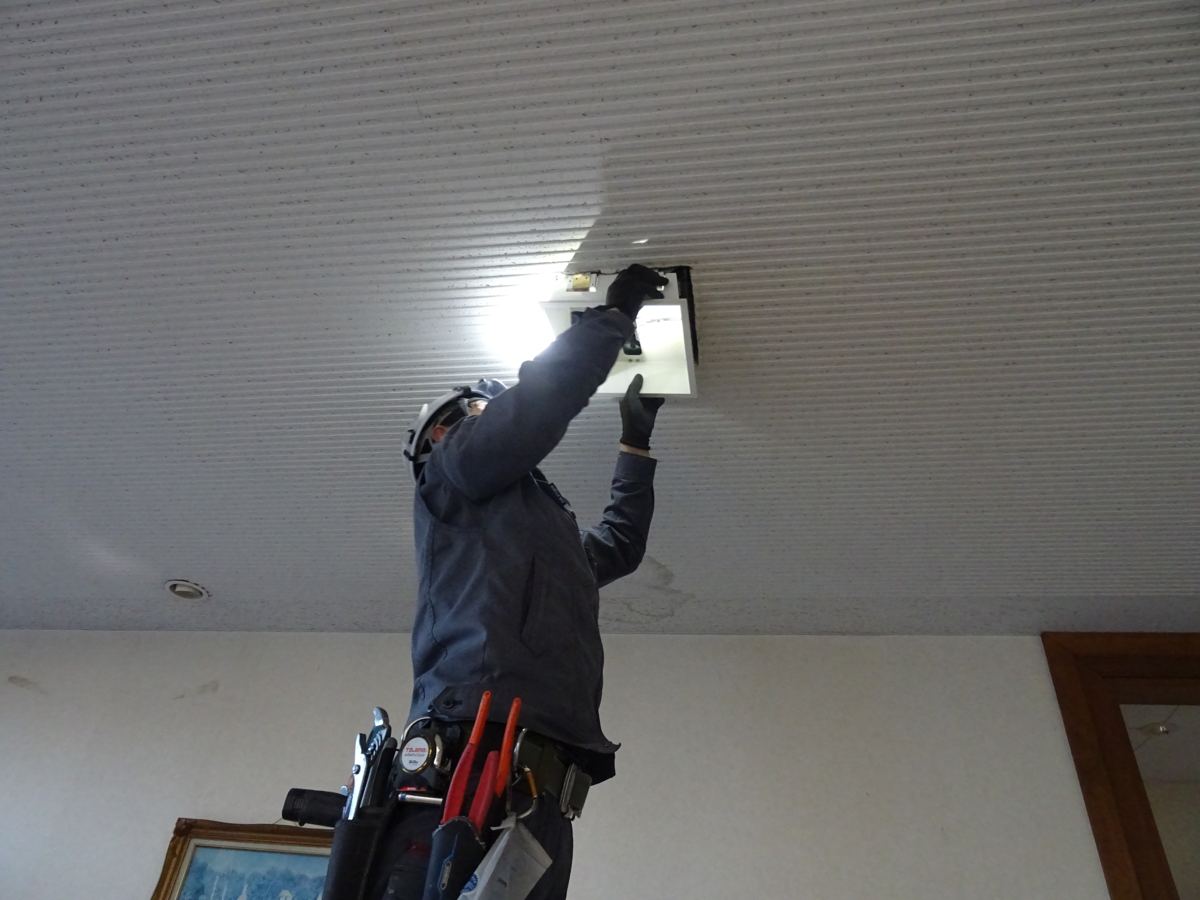 天井の照明器具を取り付けるスタッフ